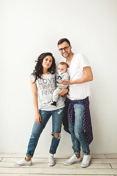 Hipster father, mother holding cute baby boy over white backgrou stock photo