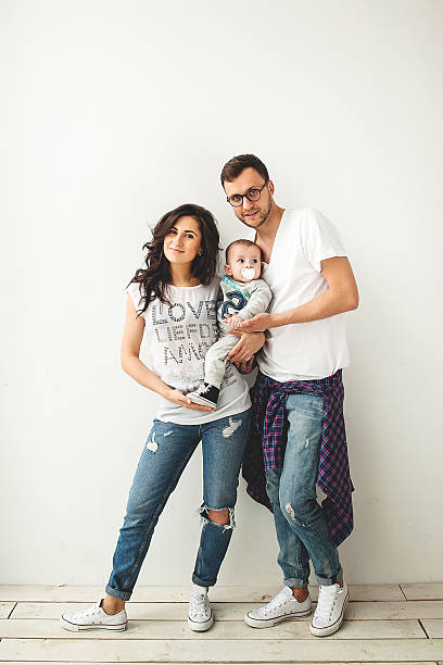 Hipster father, mother holding cute baby boy over white backgrou stock photo