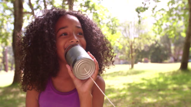 Afro girl talking into a tin can phone