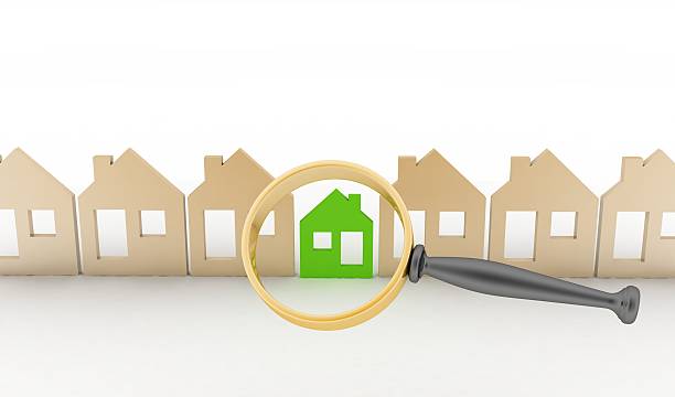 Magnifying glass selects or inspects eco-home in row of houses stock photo