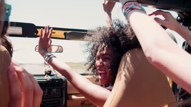Afro girl laughing with friends on a road trip vacation
