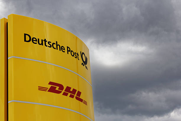 Deutsche Post and DHL sign Fuerth, Germany - April 6, 2015: detail of a yellow stele with Deutsche Post and DHL sign against dramatic sign; standing at the entrance of a Deutsche Post distribution center in Fuerth. fuerth stock pictures, royalty-free photos & images