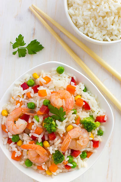 Rice with vegetables and shrimps on white background, top view