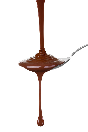 Melted chocolate poured into a spoon, isolated on the white background, clipping path included.