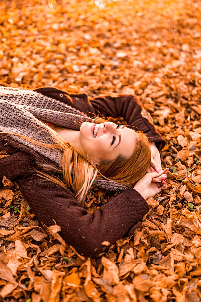 istock Relaxed woman enjoying in day while lying on autumn leaves. 469395212