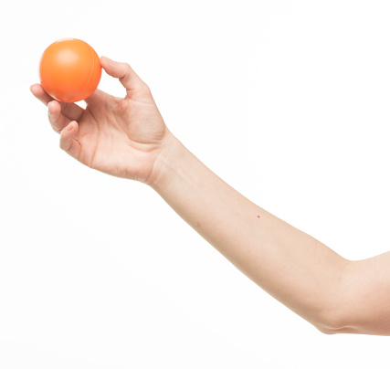 female hand with orange sponge ball, isolated on white