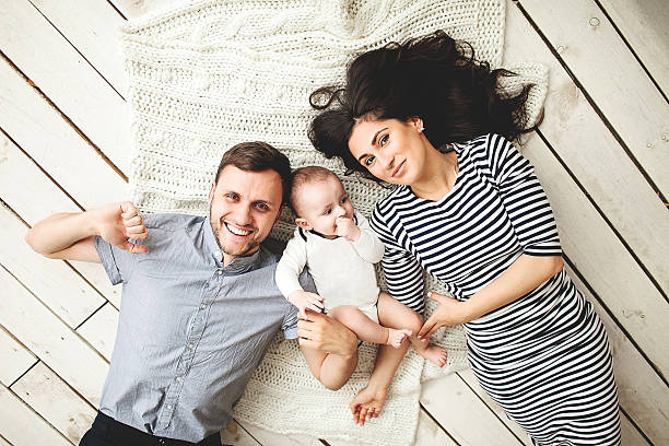 jovem pai, mãe e cute bebê deitado de chão - cheeper imagens e fotografias de stock