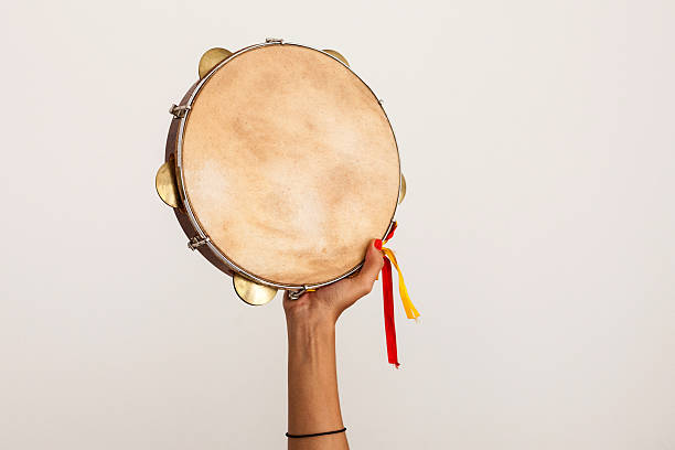 Hand holding tambourine Hand holding tambourine with yellow and red ribbons on white background percussion instrument stock pictures, royalty-free photos & images