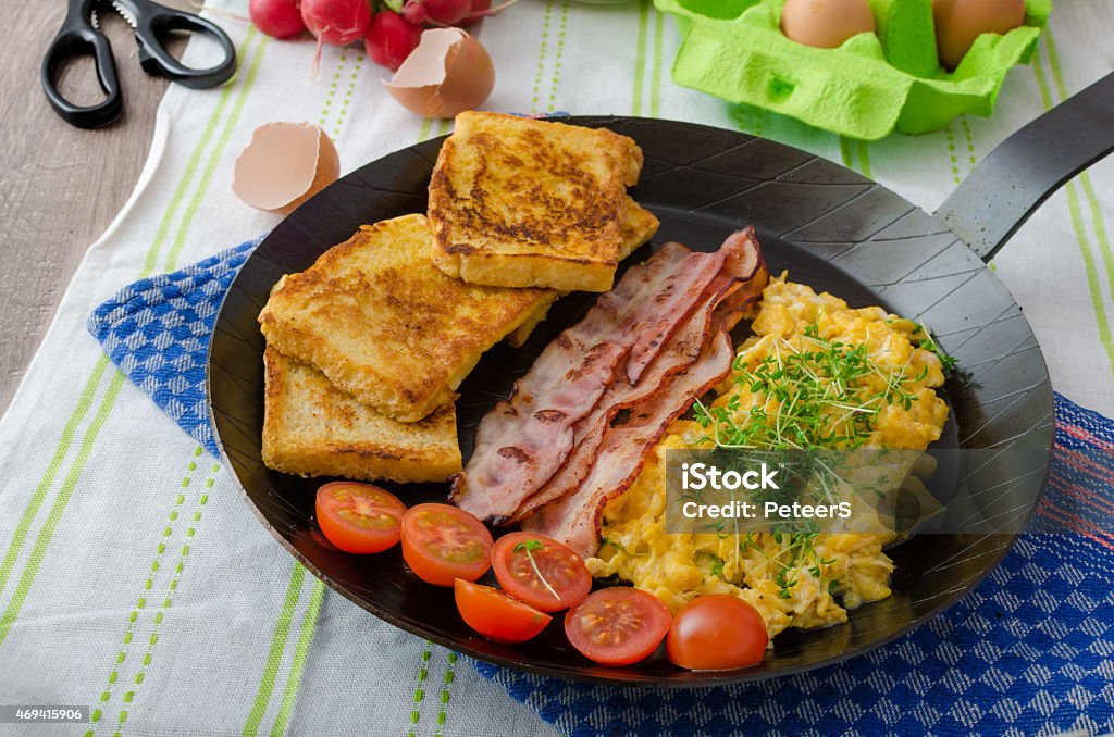 Scrambled eggs with bacon and French toast Scrambled eggs with bacon and French toast on a cast iron pan Backgrounds Stock Photo