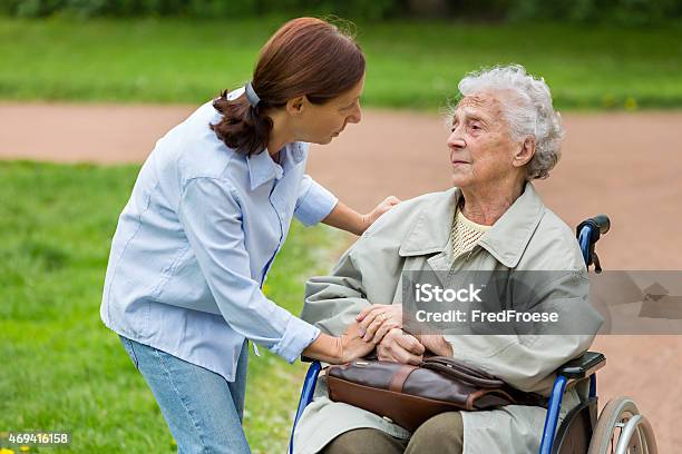 Senior Woman Sitting On Wheelchair With Carer In Park Stock Photo - Download Image Now