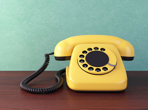 Yellow retro rotary dial telephone on wooden table. Vintage illustration.