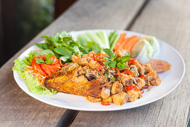 figure fish in white dish with thai herb on wood background. deep of field