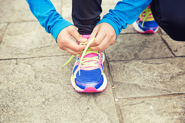 istock young woman hands tying shoelaces on trail 469438904