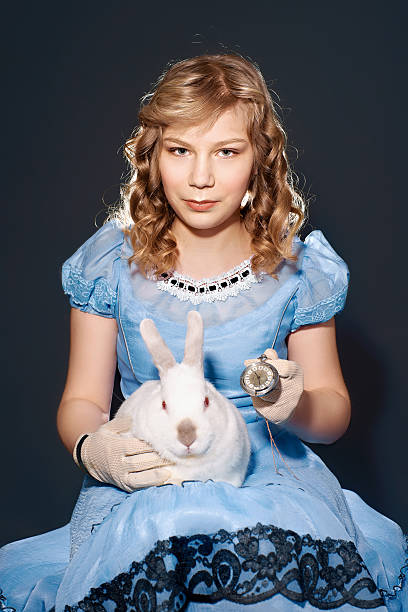 Little girl in a blue dress sitting on her lap rabbit