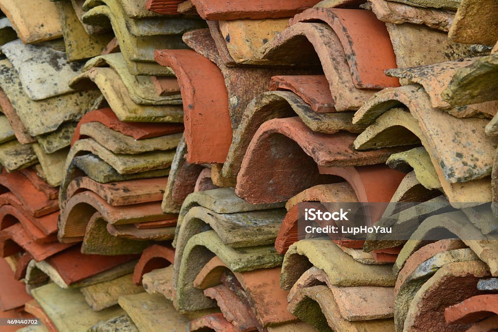 Old Charentaise farmhouse roof tiles stacked DSLR abstract picture of a stack of old farmhouse clay roof tiles in Jonzac, south west France. The tiles are multicoloured, ranging from terracotta to beige, grey and pink, all mottled with mosses and lichens.  Abstract Stock Photo