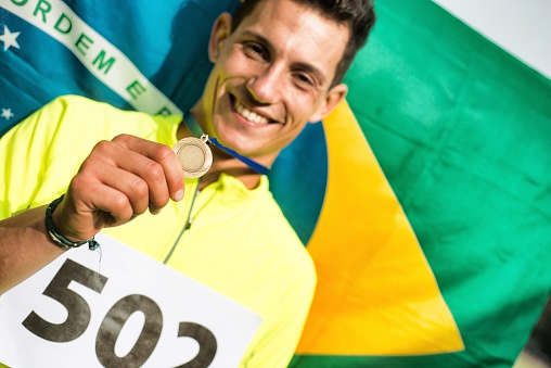 Athlete showing medals. Brazilian flag in the background