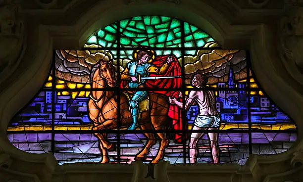 Stained glass window depicting Saint Martin cutting a part of his cloak and handing it over to a beggar, in the Basilica of San Martino in Martina Franca, Apulia, Italy.