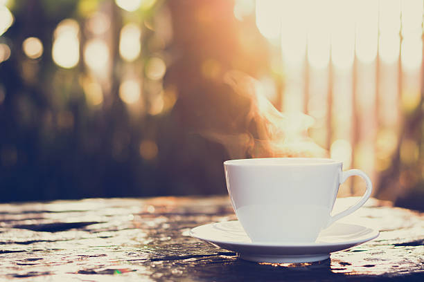 Cup of coffee on old wood table - vintage tone Hot coffee on old wood table with blur background of sunlight shining through the trees - soft focus, vintage tone coffee break stock pictures, royalty-free photos & images