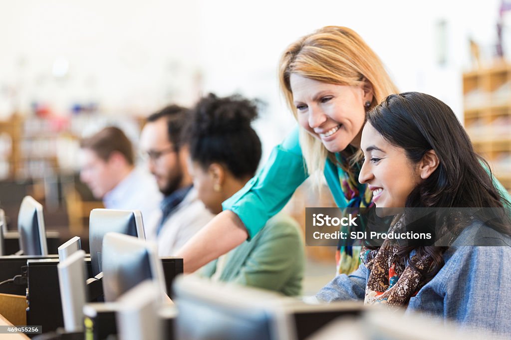 Mature Caucasian female professor assisting adult student in college library Production Tool Ref #12 Teacher Stock Photo