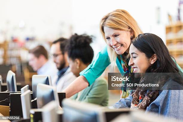 Mature Caucasian Female Professor Assisting Adult Student In College Library Stock Photo - Download Image Now