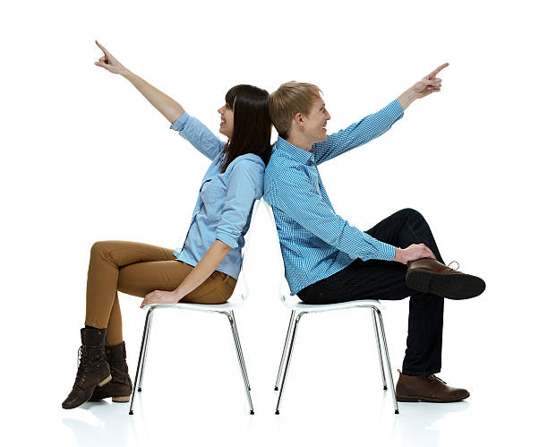 istock Smiling couple on chair and pointing away 469455950