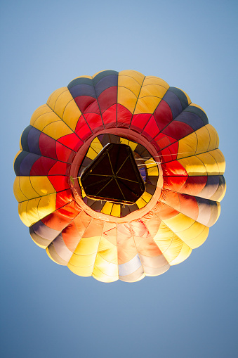 Single yellow hot air balloon floating through the clear blue sky during the day. Lots of copy space.