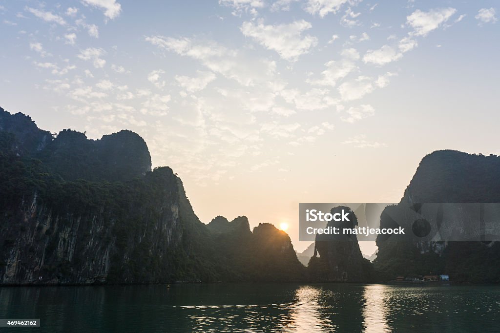 Sunrise over rock formations in Halong bay Vietnam Sunrise over rock formations in Halong bay, north Vietnam. Sun has just risen over the jagged rocks in the centre of the image, making them dramatic silhouettes against the sky. Asia Stock Photo