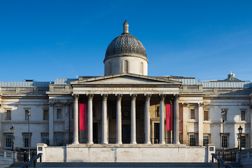 People walk next to the Horse Guards building in central London England UK on a sunny day.