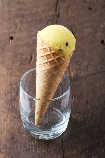 yellow passion fruit ice cream cones  in clear glasses on dark wooden background