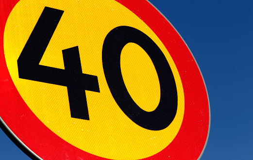 Close-up of a Swedish speed limit 40 kmh road sign on blue sky.