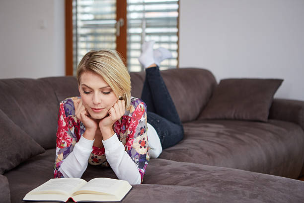 istock woman enjoying reading a book at home lying on the 469514278