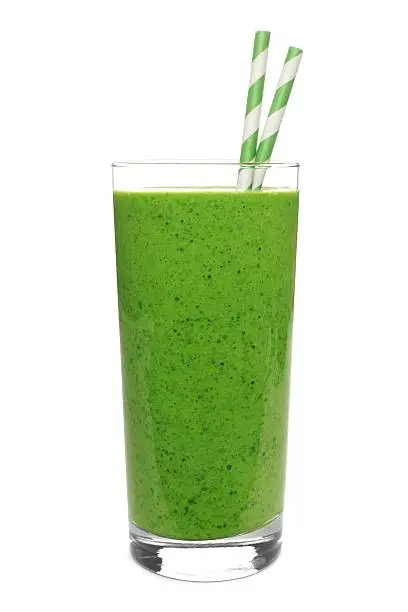 Photo of Green smoothie in glass with straws isolated on white