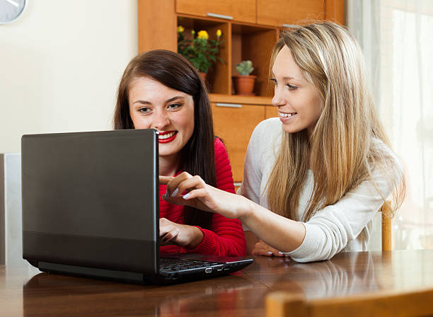 women looking to laptop at table women looking to laptop at table in home or office wonderingly stock pictures, royalty-free photos & images