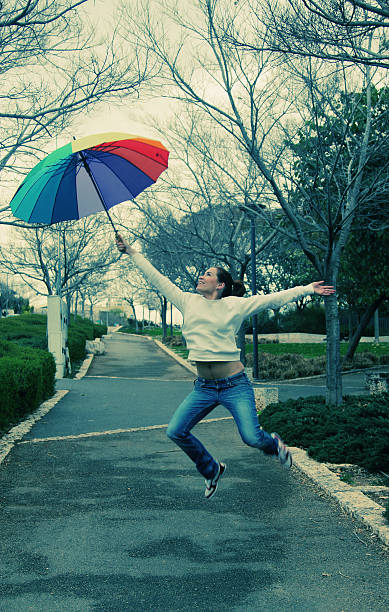 istock Young woman holding big rainbow umbrella 469523391