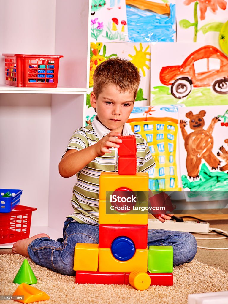 Kid boy in kindergarten Little boy  in kindergarten stacking block. Painting  background. 2015 Stock Photo