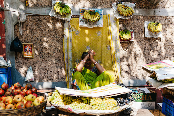 Kolkata, India - March 6, 2014: Woman covers her face from the bright sun while selling bananas and other fruit on the streets of Kolkata, India