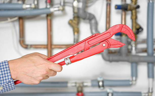 istock plumber holding pipe wrench with pipe system in background blur 469545768