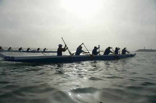 Group of multiethnic people paddling outrigger canoes in race