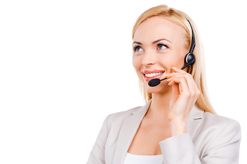 Confident mature customer service representative adjusting her headset and smiling while standing against white background