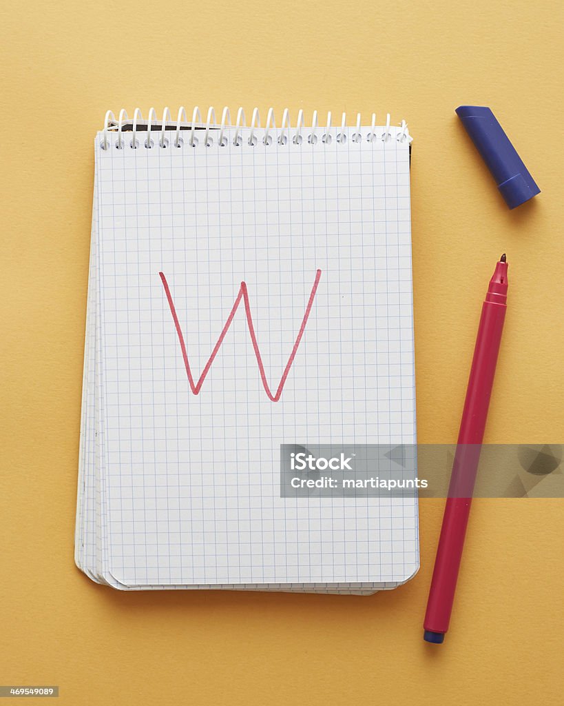 W letter handwritten in notebook W letter handwritten in notebook page on yellow background alphabet Above Stock Photo