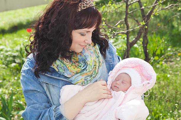 istock Young mother with newborn baby in outdoors at spring day 469549364