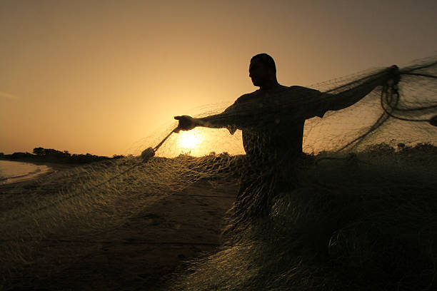 Silhouette of fisherman pulling fishing nets at Derrumbao Beach stock photo