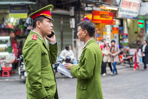 Hanoi, Vietnam - February 11, 2015: Police men on patrol in the old quarter of Hanoi. The 36 old streets and guilds of the old quarter are a major tourist attraction.