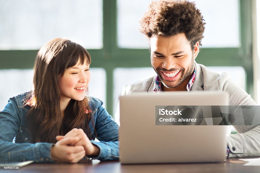 Two young coworkers using a laptop together Two young coworkers working together on a laptop Trainee Stock Photo