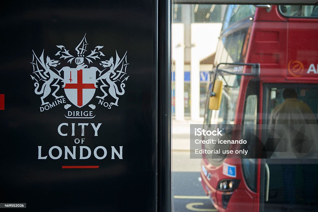 City of London bus stop sign London, UK - April 6, 2015: Detail of black City of London banner in bus stop featuring its coat of arms, with front of red bus in the background. 2015 Stock Photo