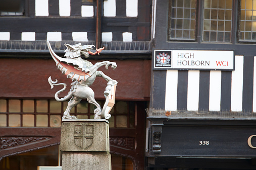 London, UK - April 7, 2015: Profile of City of London coat of arms dragon statue, with High Holborn street sign in the blurred background.