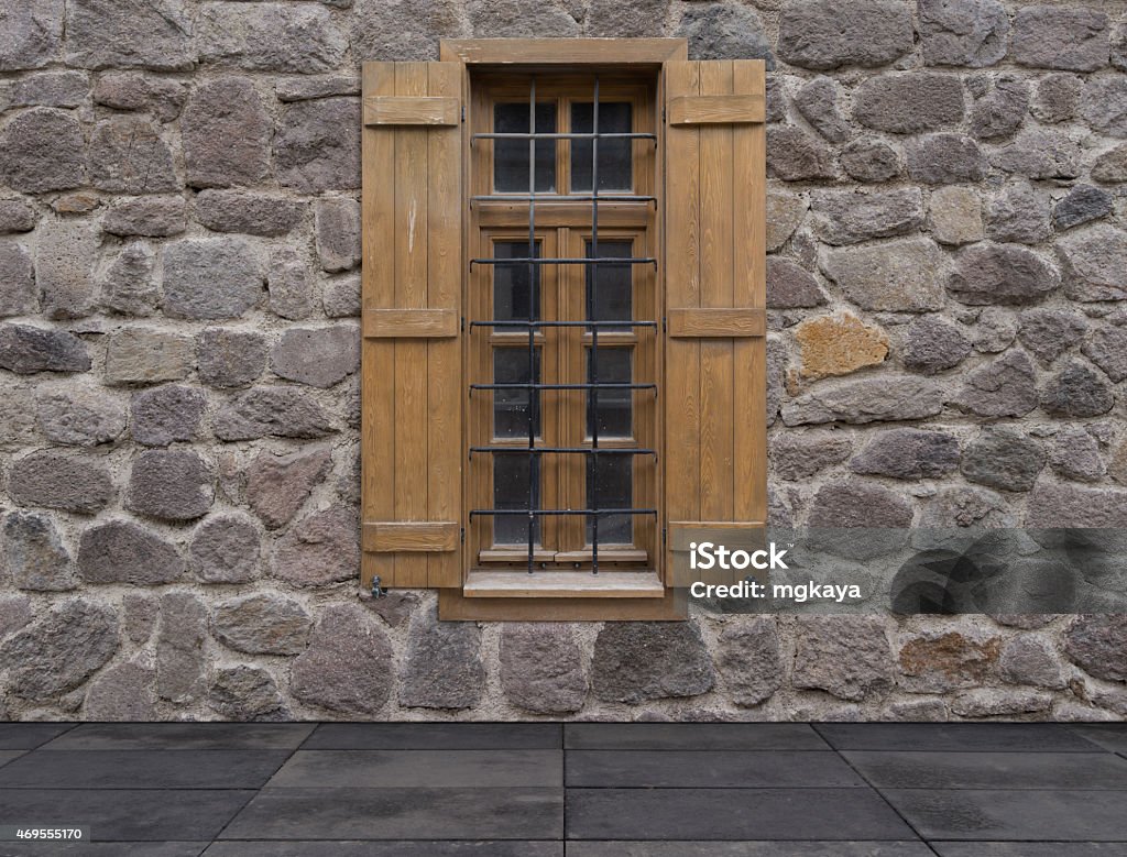 Old Window with Shutters Against a Stone Wall Old window with wooden exterior shutters against a stone wall with sidewalk. 2015 Stock Photo