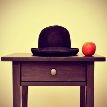 picture of a bowler hat and an apple on a bureau, homage to Rene Magritte painting The Son of Man, with a retro effect