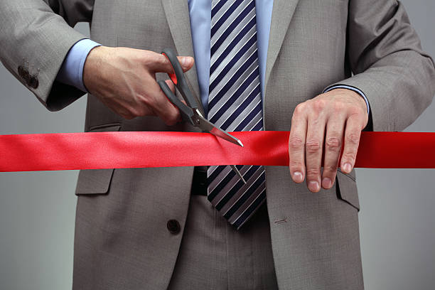 New business venture cutting a red ribbon Cutting a red ribbon with scissors concept for new business venture or opening ceremony opening event stock pictures, royalty-free photos & images