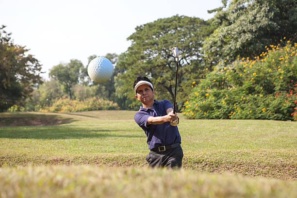 golfer chipping golf ball out of a sand trap - 低切球 個照片及圖片檔